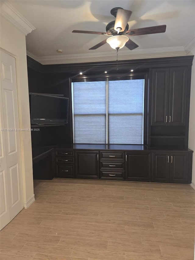 spare room featuring ornamental molding, light wood-type flooring, and a ceiling fan