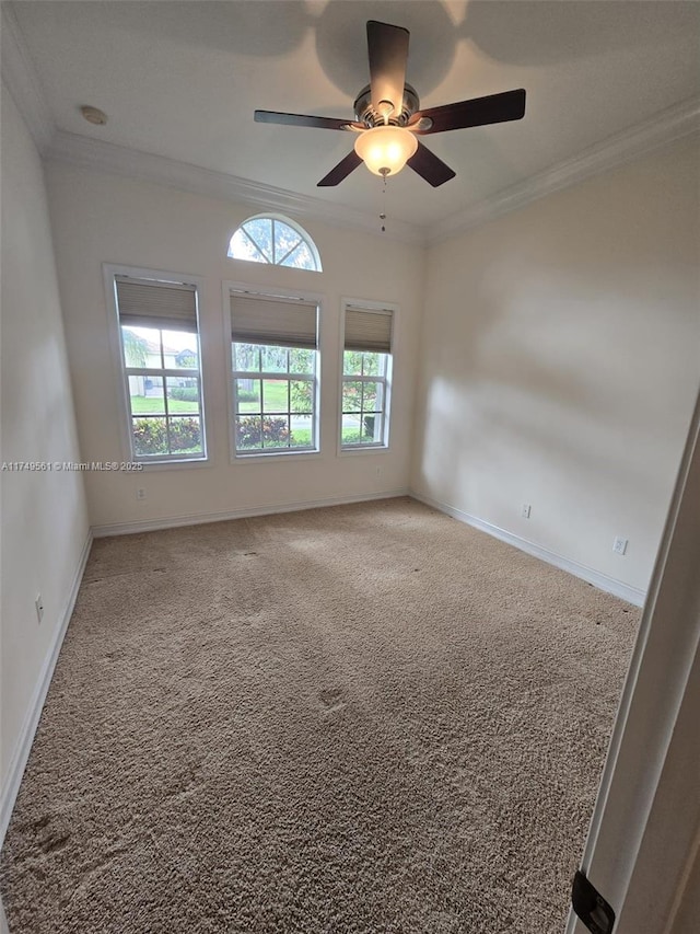 carpeted empty room featuring baseboards, ornamental molding, and ceiling fan