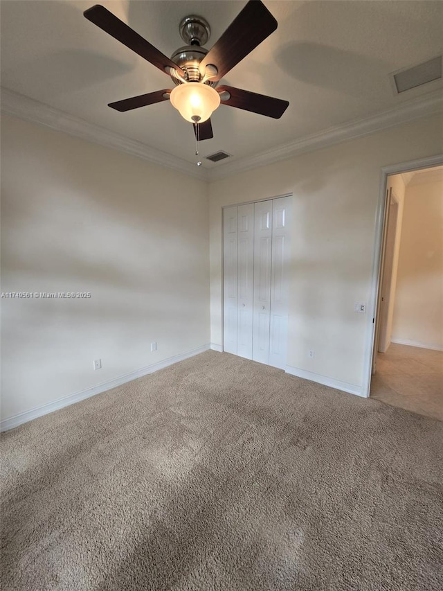 empty room with carpet flooring, visible vents, and crown molding