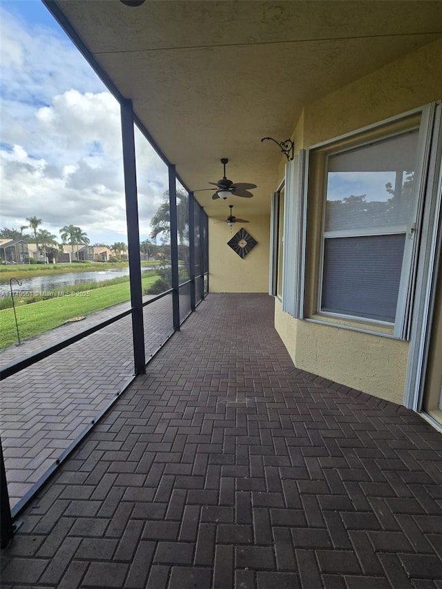 view of patio / terrace featuring ceiling fan, a water view, and a balcony