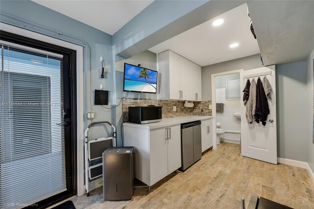 kitchen with tasteful backsplash, black microwave, light wood-style floors, light countertops, and white cabinetry