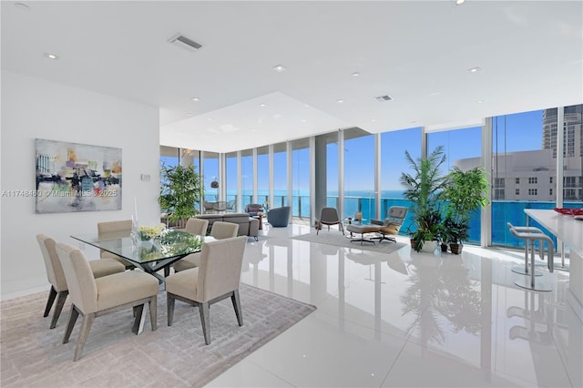 dining area featuring a water view, a healthy amount of sunlight, visible vents, and floor to ceiling windows