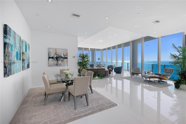 dining space with a wall of windows, a water view, and visible vents