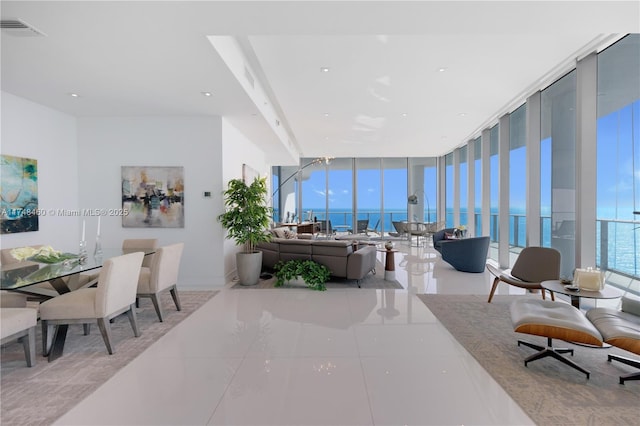 living area with a water view, tile patterned flooring, expansive windows, and visible vents