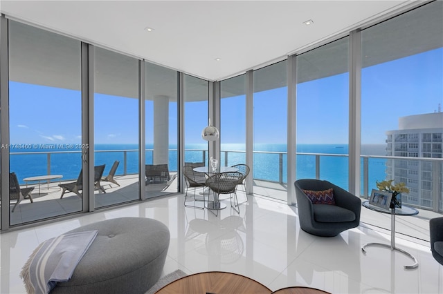 living area with floor to ceiling windows, a water view, and light tile patterned flooring