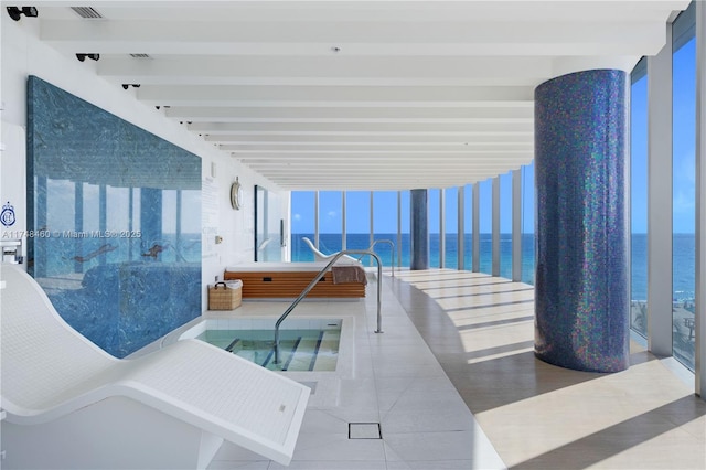 view of swimming pool with an indoor hot tub and a water view