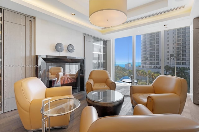 sitting room featuring a raised ceiling, a city view, a fireplace, and wood finished floors