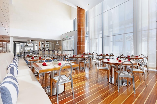 dining space featuring wood finished floors and a towering ceiling