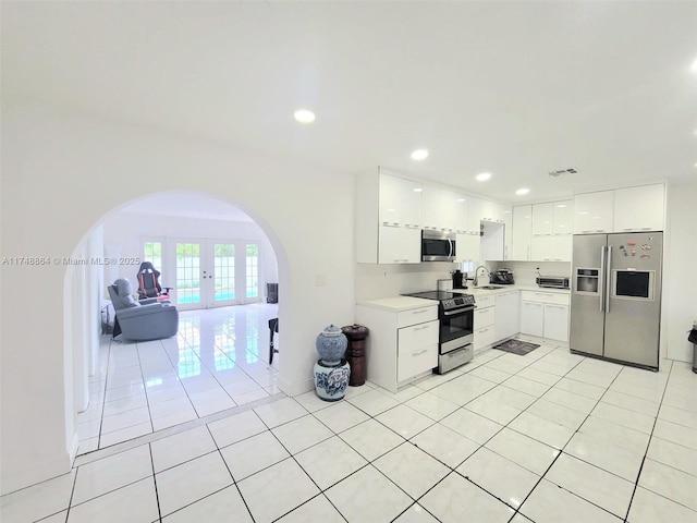 kitchen with arched walkways, visible vents, white cabinetry, light countertops, and appliances with stainless steel finishes