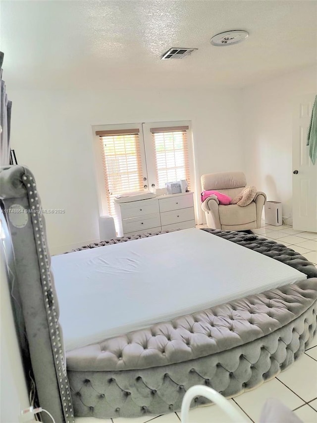 bedroom featuring visible vents, a textured ceiling, and tile patterned floors