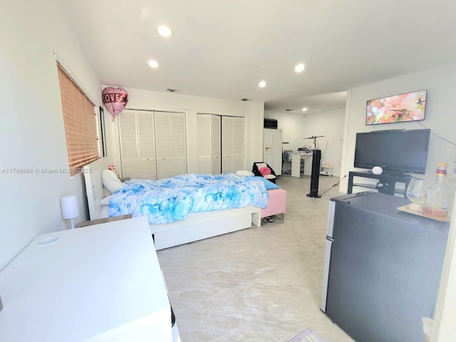 bedroom featuring white refrigerator with ice dispenser, recessed lighting, and multiple closets