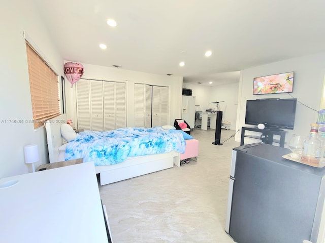 bedroom featuring visible vents, freestanding refrigerator, concrete flooring, multiple closets, and recessed lighting