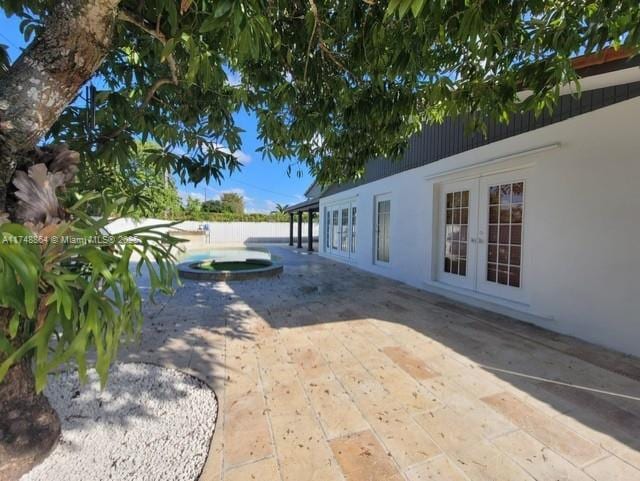 exterior space featuring an in ground hot tub, fence, a patio, and french doors