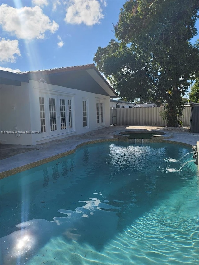 view of swimming pool with a fenced in pool, french doors, a patio, fence, and an in ground hot tub