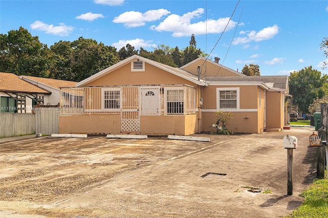 view of front of home with stucco siding and fence