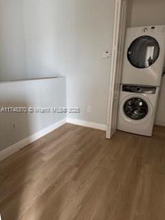 washroom with dark wood-style floors, laundry area, stacked washer / dryer, and baseboards