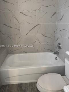 bathroom featuring washtub / shower combination, toilet, and wood finished floors