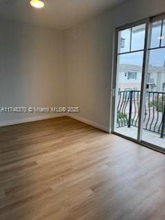 spare room with baseboards and wood finished floors