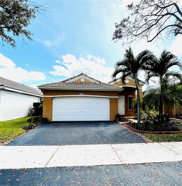 ranch-style home featuring driveway, an attached garage, a tiled roof, and stucco siding