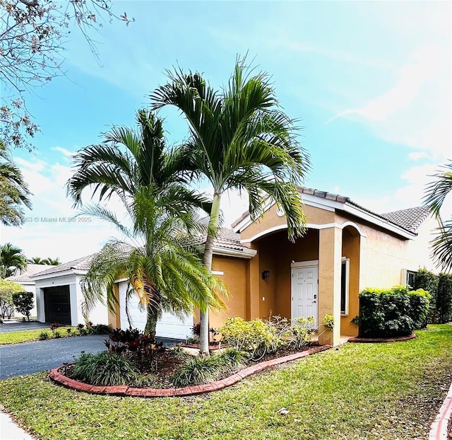 view of front of house with a garage, driveway, a front lawn, and stucco siding