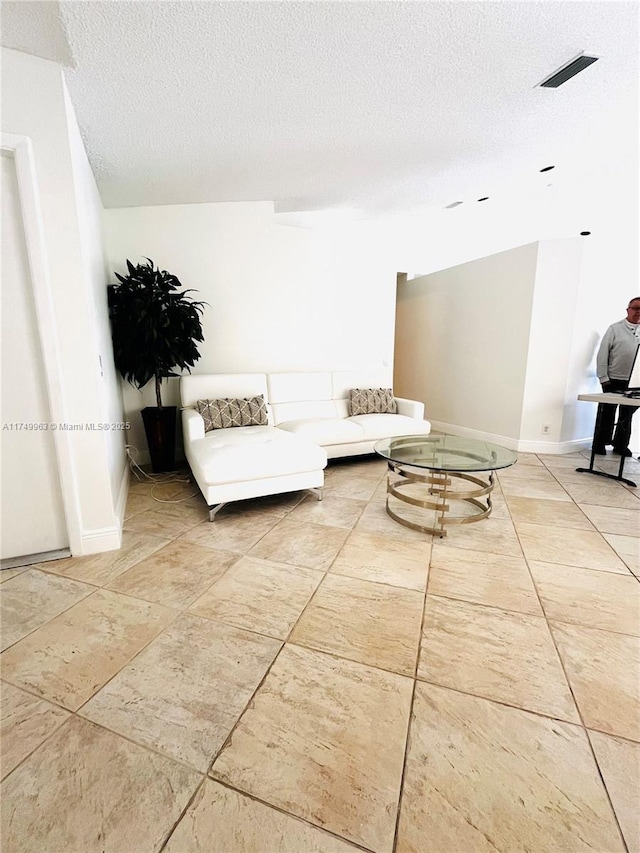 unfurnished living room with a textured ceiling, visible vents, and baseboards