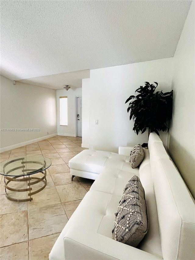 tiled living room with baseboards and a textured ceiling