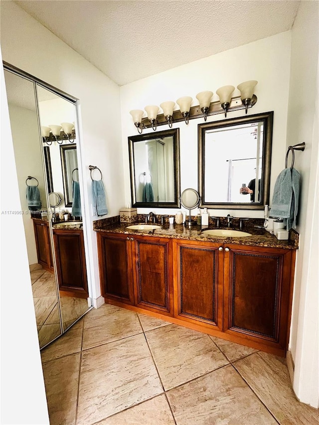 bathroom with a textured ceiling, double vanity, and a sink