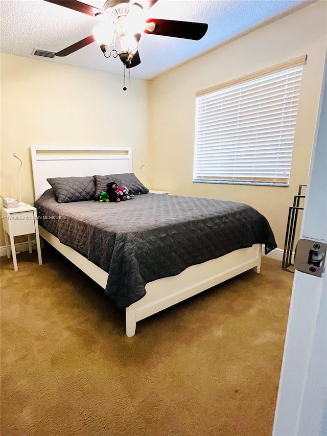 bedroom with carpet flooring, ceiling fan, visible vents, and a textured ceiling