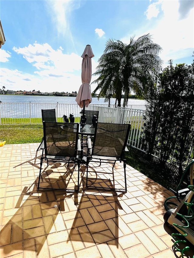 view of patio featuring a water view, fence, and outdoor dining area