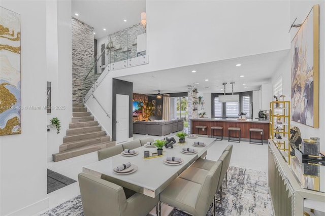 dining room featuring recessed lighting, ceiling fan, a towering ceiling, and stairs