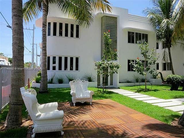 back of house with a yard, fence, and stucco siding