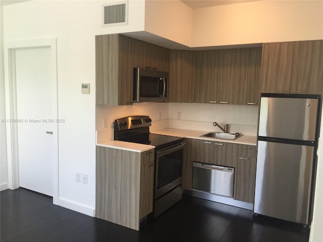 kitchen with visible vents, dark wood-style floors, appliances with stainless steel finishes, light countertops, and a sink