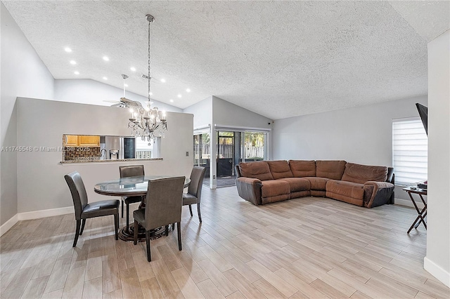 dining room with a textured ceiling, baseboards, vaulted ceiling, light wood-type flooring, and an inviting chandelier