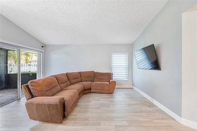 living room featuring vaulted ceiling, light wood finished floors, a textured ceiling, and baseboards