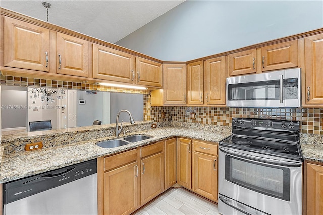 kitchen with stainless steel appliances, vaulted ceiling, a sink, and light stone countertops