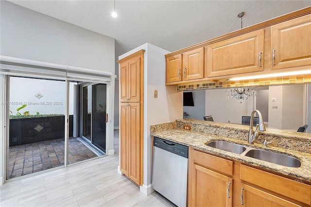 kitchen featuring a textured ceiling, stainless steel dishwasher, a sink, and light stone counters