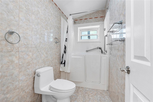 bathroom featuring toilet, shower / bath combo with shower curtain, tile patterned flooring, and tile walls