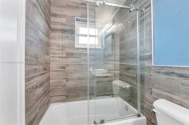 bathroom with toilet and combined bath / shower with glass door