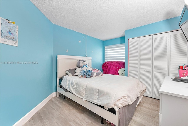 bedroom with a textured ceiling, light wood finished floors, and baseboards