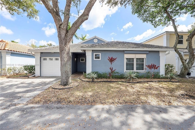 ranch-style home with driveway, an attached garage, and stucco siding