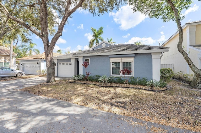 ranch-style house with driveway, an attached garage, and stucco siding