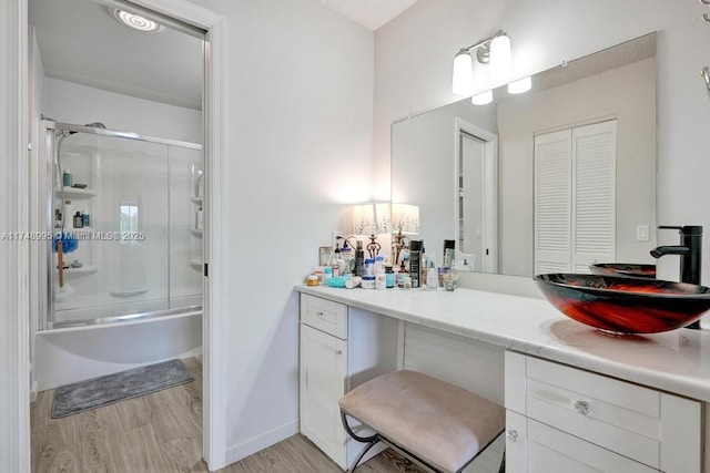 full bathroom featuring bath / shower combo with glass door, a closet, wood finished floors, and vanity