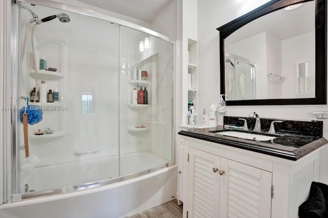 bathroom featuring bath / shower combo with glass door, wood finished floors, and vanity