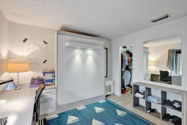 interior space with light wood finished floors, a closet, visible vents, and a textured ceiling