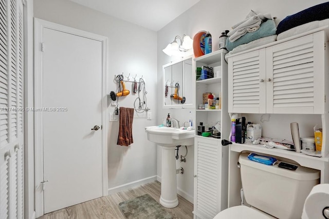 bathroom with toilet, baseboards, a closet, and wood finished floors