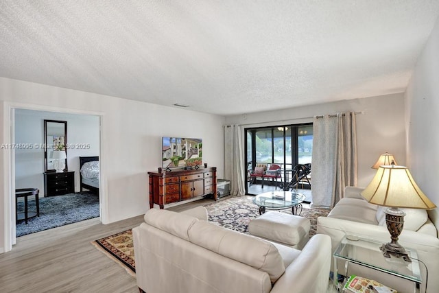 living area featuring a textured ceiling, visible vents, and light wood-style floors