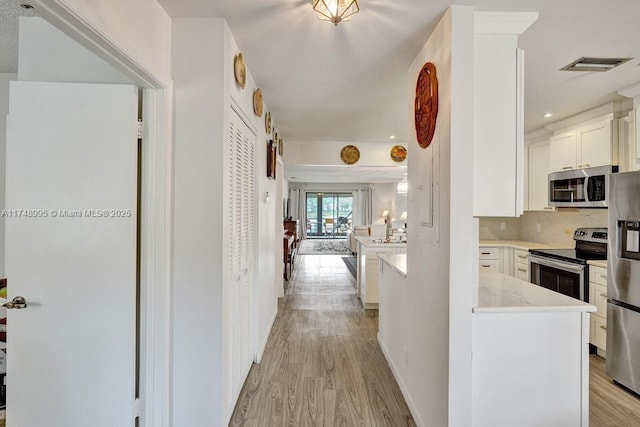 hall featuring light wood-type flooring, visible vents, baseboards, and recessed lighting