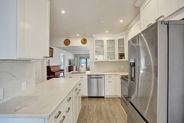 kitchen with appliances with stainless steel finishes, white cabinets, glass insert cabinets, and tasteful backsplash