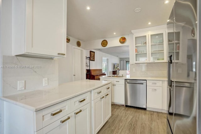 kitchen with light wood finished floors, decorative backsplash, glass insert cabinets, white cabinets, and dishwasher