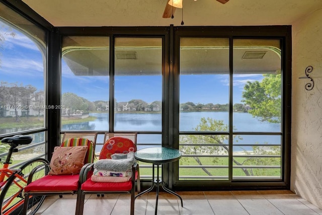 sunroom / solarium with a water view, plenty of natural light, and a ceiling fan